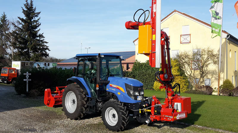 Blauer ISEKI-Traktor mit rotem Auslegemulcher